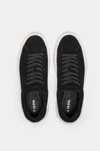 Sneakers daim noir portées lifestyle homme élégant