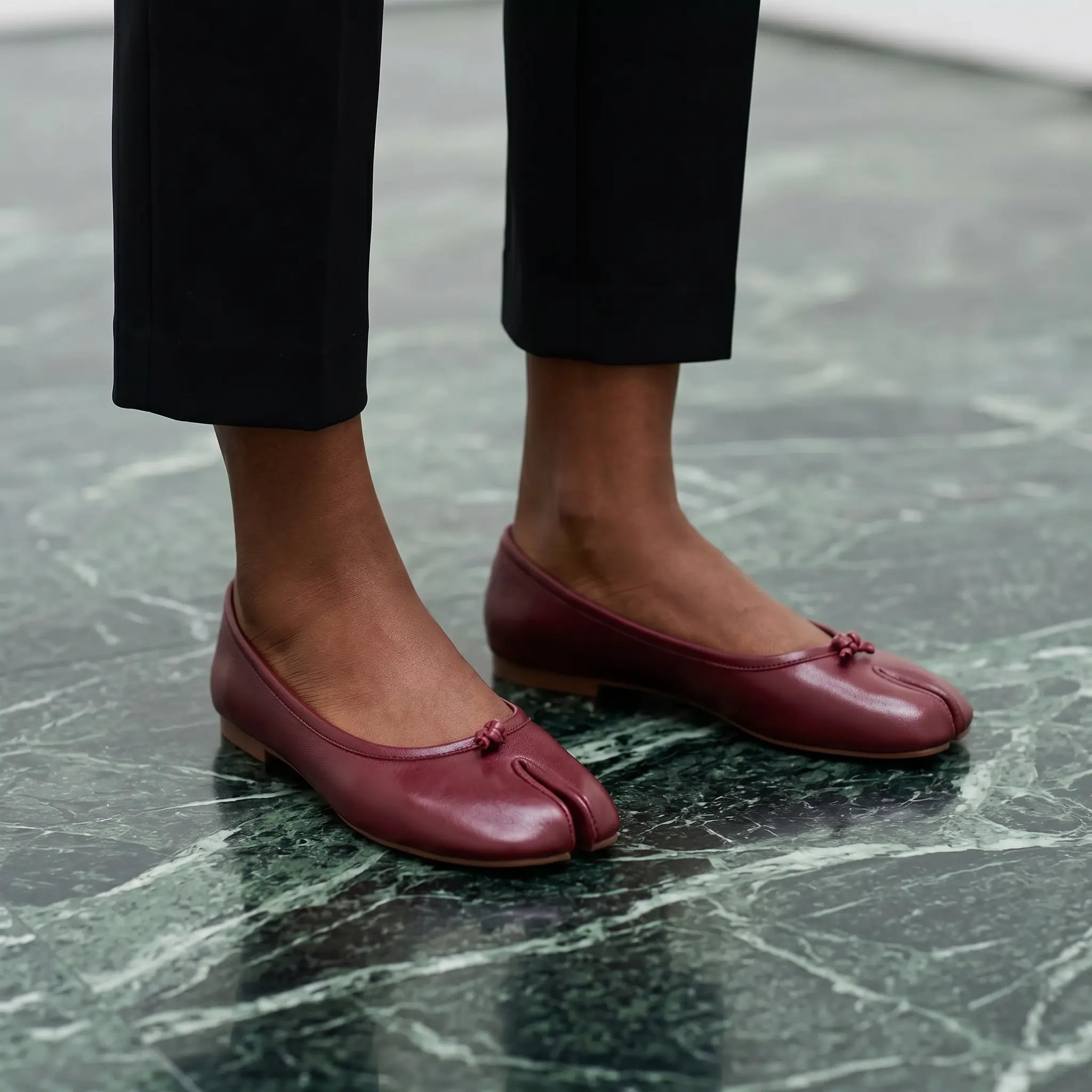 Ballerines bout fendu rouge cramoisi portées sur un sol en marbre vert, design élégant
