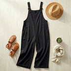 Salopette large en coton lin noir en flat-lay avec chapeau de paille et sandales tressées