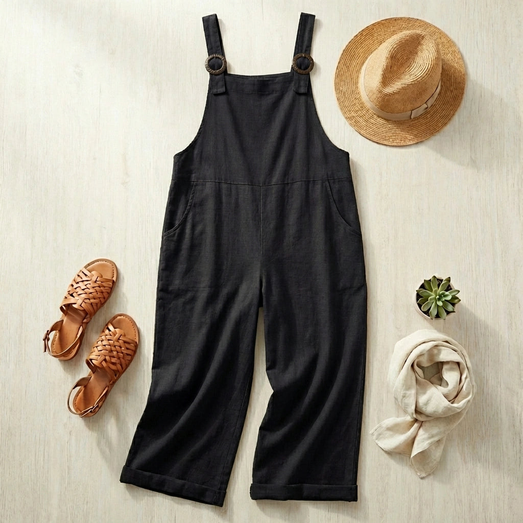 Salopette large en coton lin noir en flat-lay avec chapeau de paille et sandales tressées