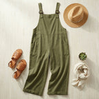 Salopette coton lin vert olive en flat-lay avec chapeau de paille et accessoires d'été