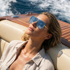 Femme portant des lunettes aviateur dégradées bleues sur un yacht de luxe